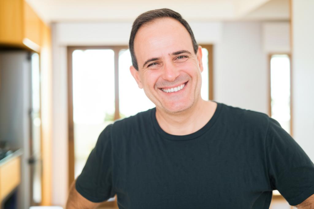 Smiling middle-aged man looking confident and energetic, perhaps with a subtle background suggesting a happy home.