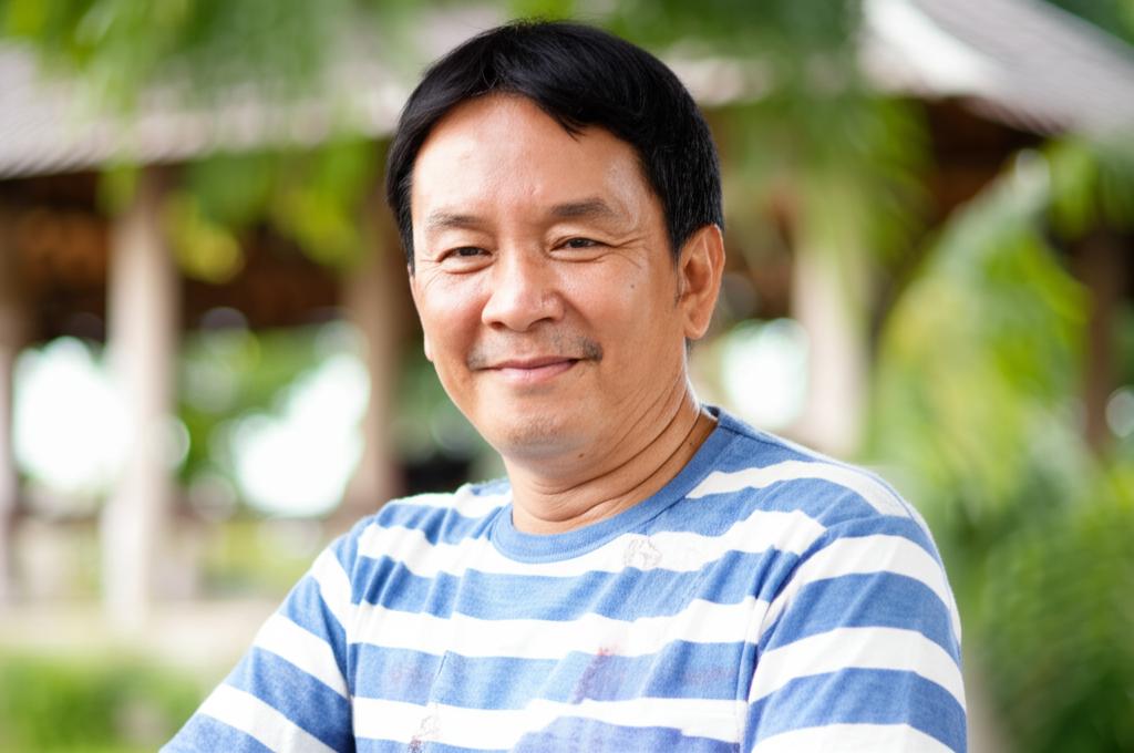 Middle-aged man in Thailand looking energetic and happy, perhaps playing with family or enjoying a hobby, realistic style
